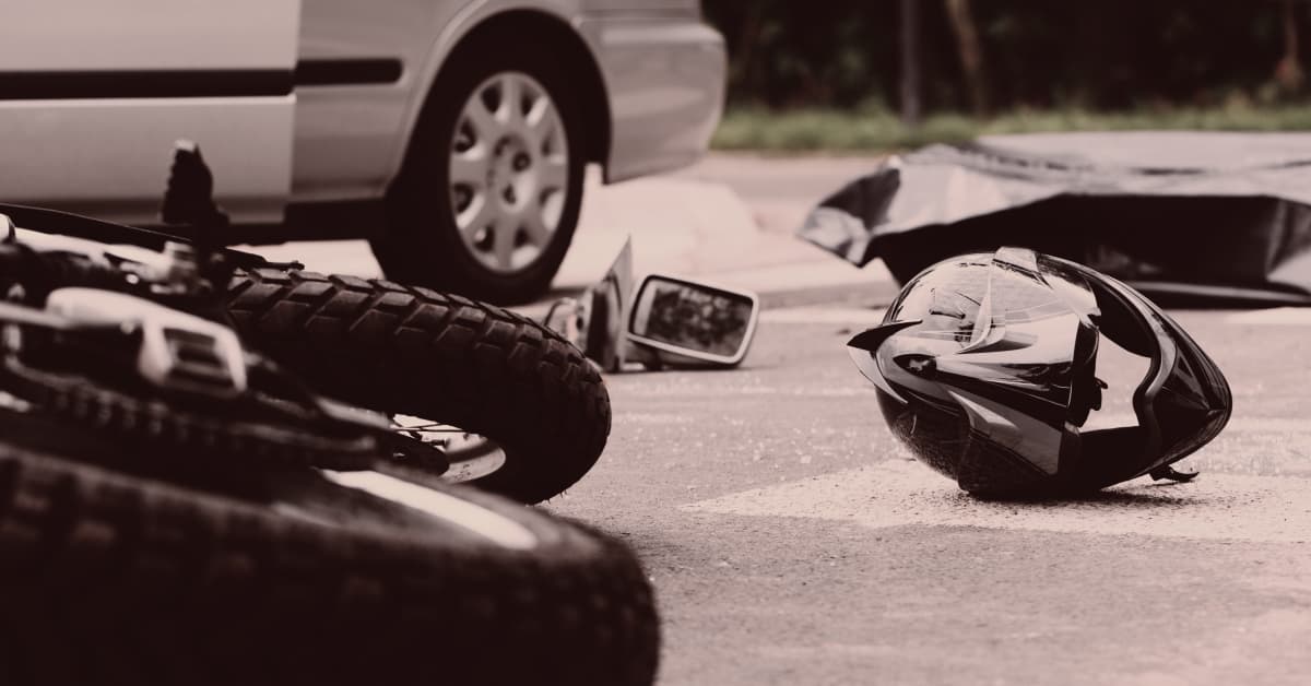 A motorcycle accident with a car missing parts and a motorcycle helmet in the street | Alexander Shunnarah Trial Attorneys