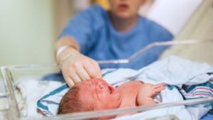 A mother reaches for her child in the NICU, illustrating the kind of event that may need a Birmingham medical malpractice lawyer.