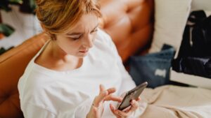 A frustrated woman taps on her phone screen, portraying the common scenario of dealing with insurance dispute tactics.