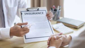 A homeowner reviews an insurance denial letter at a desk with documents. Learn what to do when a homeowner's insurance claim is denied in Alabama.