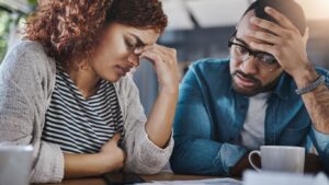 A former employee reviews employment documents at a desk with her partner. Signs of wrongful termination may include sudden firing after a complaint, discriminatory remarks, or shifting explanations.