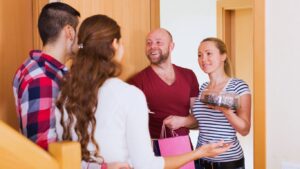 A couple greets their visitors for a small party, illustrating the question of “What is premises liability?”