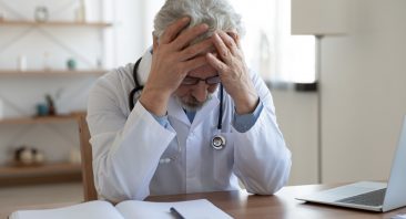 Tired depressed old male doctor feels desperate thinking of medical problem feels burnout at work. Worried upset senior physician regrets medical malpractice suffers from guilt sits alone in office.