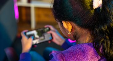 A young girl plays on a handheld video game console. She may be addicted and her parents may want to file a gaming addiction lawsuit.