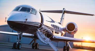 A private jet is parked in an airport while the sun is setting.