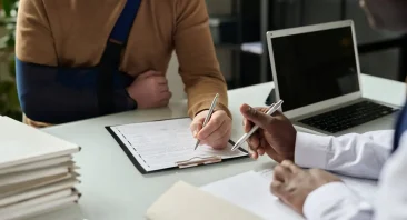 A Huntsville, AL accident lawyer reviews case details with an injured client at a law office consultation table.