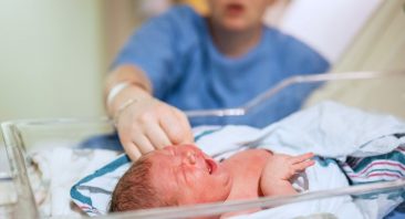 A mother reaches for her child in the NICU, illustrating the kind of event that may need a Birmingham medical malpractice lawyer.