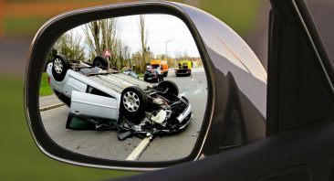A rideshare accident is viewed through a side mirror, illustrating the type of scene where a Birmingham rideshare accident attorney would be helpful.