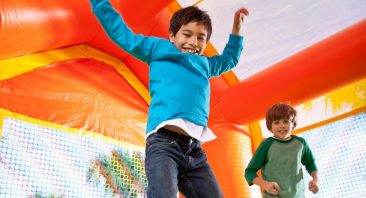 Two young boys play in a colorful inflatable bounce house, illustrating bounce house injury liability.