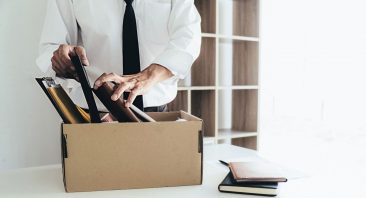 An employee packing a box of belongings at a desk after being fired, illustrating a wrongful termination claim.
