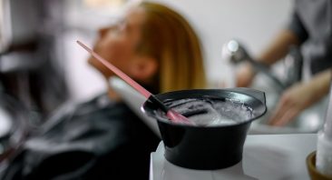 A stylist applying hair color at a salon station with foils and product bowls, illustrating hair salon injury risks.
