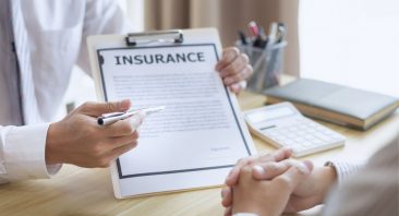 A homeowner reviews an insurance denial letter at a desk with documents. Learn what to do when a homeowner's insurance claim is denied in Alabama.
