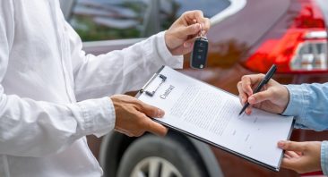 A person picking up rental car keys at a counter after a car accident, illustrating rental coverage duration.