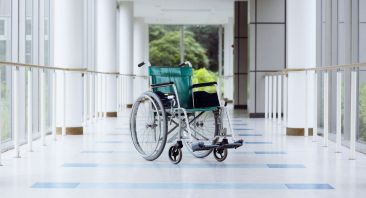 An empty wheelchair near an open nursing home exit door, illustrating the danger of nursing home elopement.