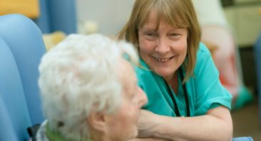 A caretaker smiles at an elderly woman in a nursing home. If things go awry, the woman's family may need an Orlando nursing home abuse attorney.