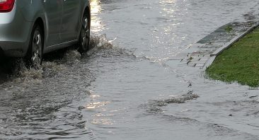 A silver vehicle crosses a flood street