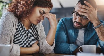 A former employee reviews employment documents at a desk with her partner. Signs of wrongful termination may include sudden firing after a complaint, discriminatory remarks, or shifting explanations.