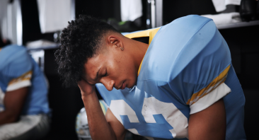 An athlete clutches his head after a football injury, illustrating the concept of what to do after a concussion.