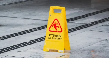 A wet floor sign sits on a slick floor aisle, showing the kind of hazard that can cause a slip and fall accident.